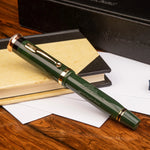 The Brunel GWR Pen rollerball capped, deep green resin with gold trim, resting on a desk